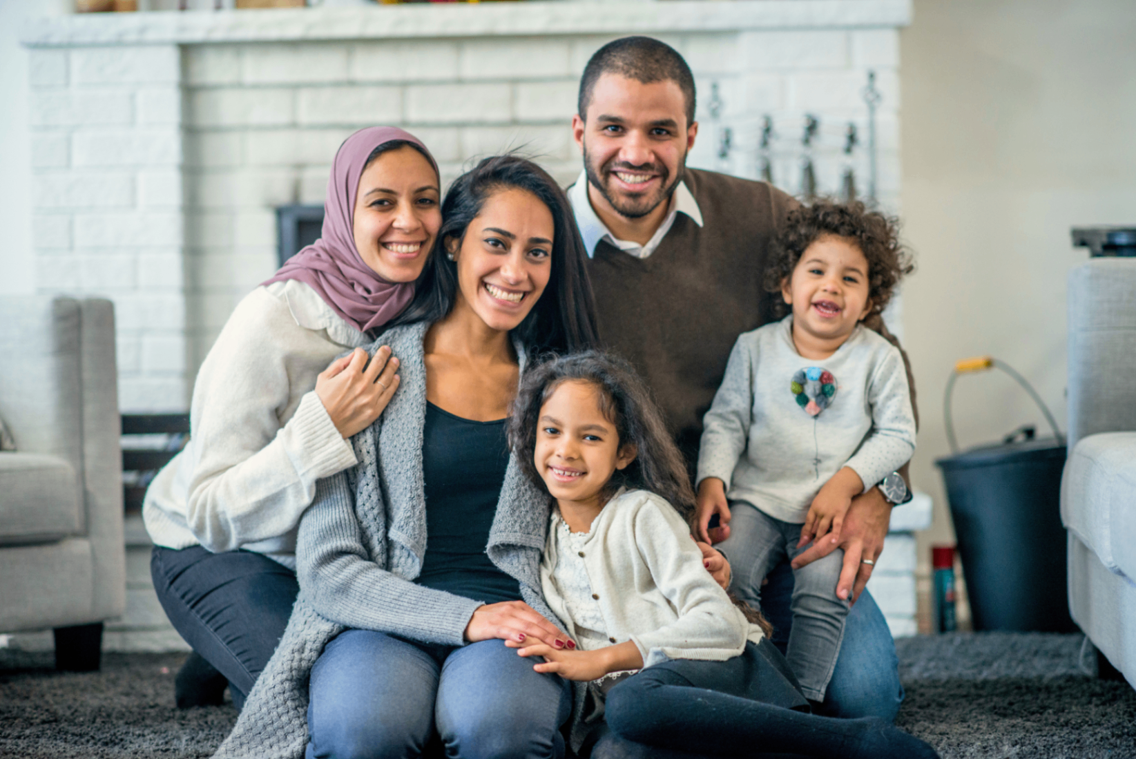 A smiling family together indoors, showing connection and community support.